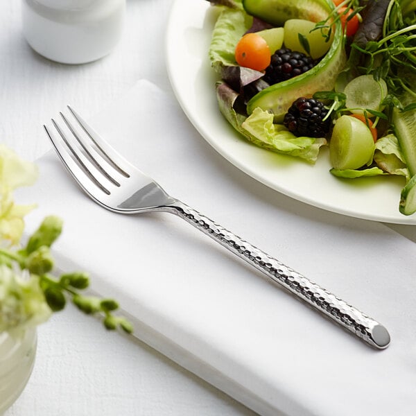 An Acopa Iris stainless steel salad fork on a plate of salad.