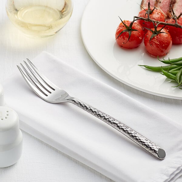 An Acopa stainless steel dinner fork on a plate with food on it.