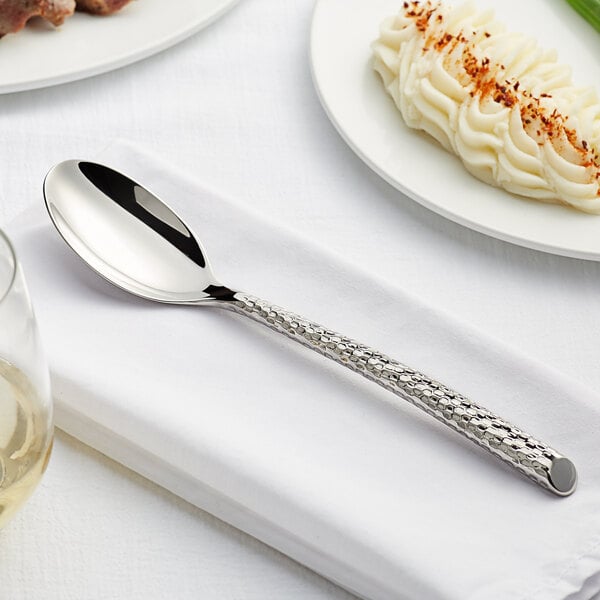 An Acopa stainless steel dinner spoon on a white plate.