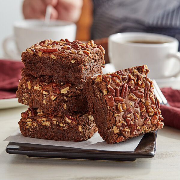 A stack of David's Cookies Pecan Brownies with nuts on a plate.
