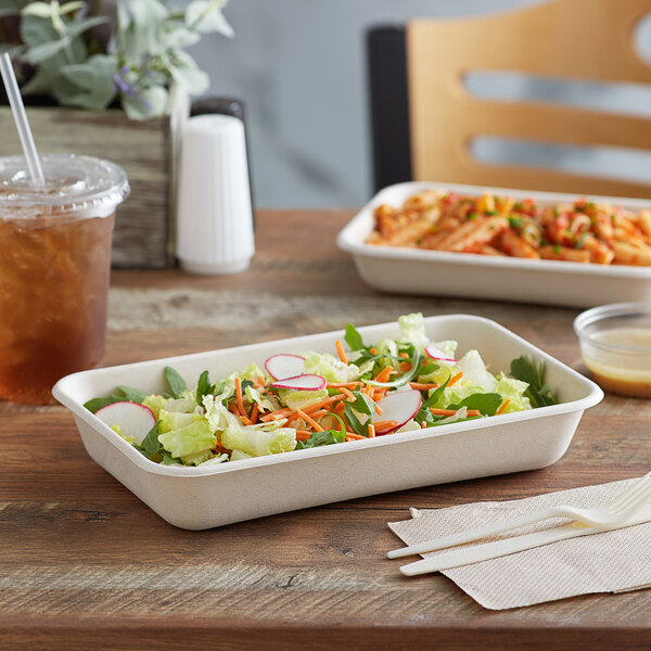 A salad in an Eco-Products natural sugarcane rectangle take-out container on a table.