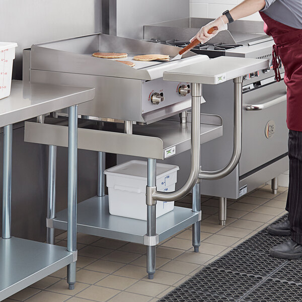 A man cooking on a Regency stainless steel equipment stand in a commercial kitchen.
