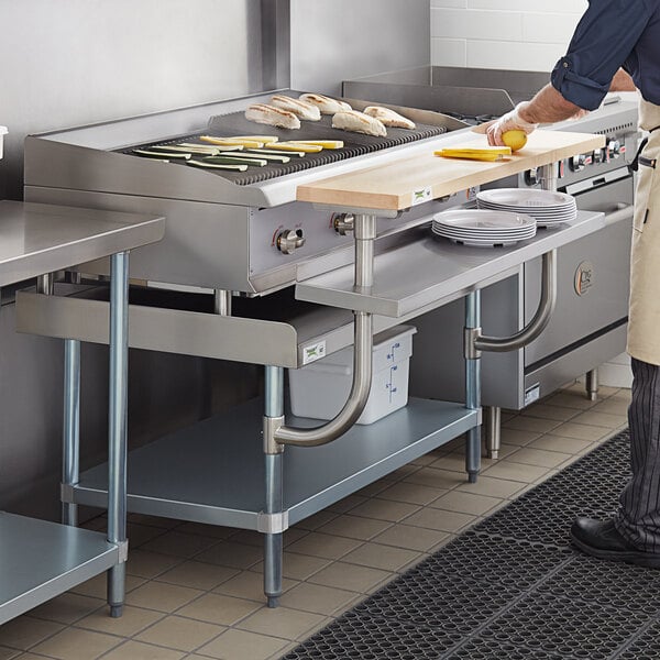 A man cooking food on a Regency stainless steel equipment stand in a commercial kitchen.
