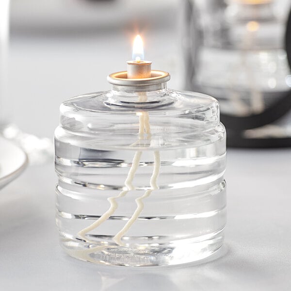 A glass container with a Leola Candle liquid fuel cartridge and a lit candle inside.