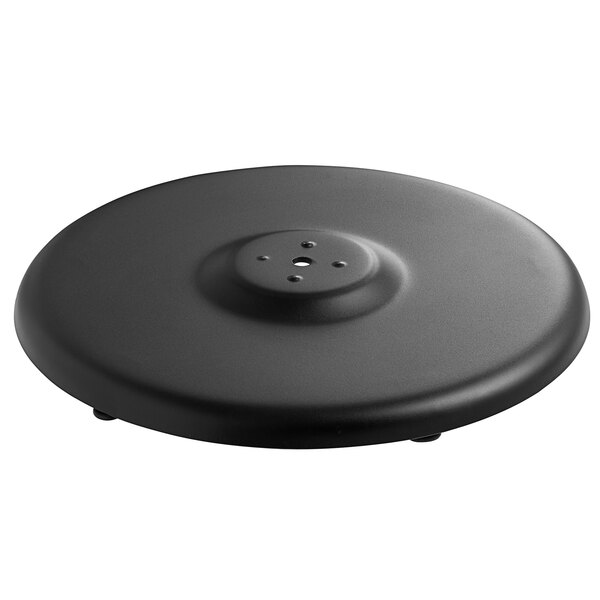 A black round Lancaster Table & Seating Excalibur outdoor table base plate with a hole in the center.