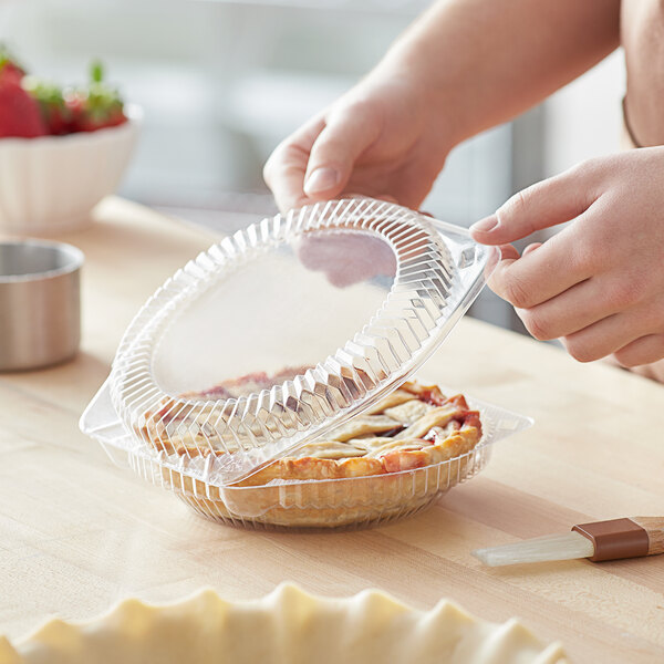 A person holding a Choice clear plastic container with a pie inside.