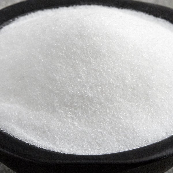 A white bowl of Regal MSG powder on a white table.