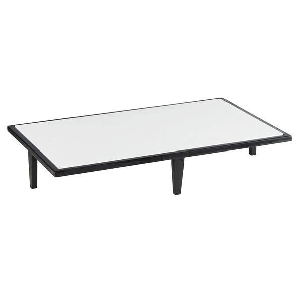 A white rectangular table with a black Cal-Mil Monterey Riser on top.