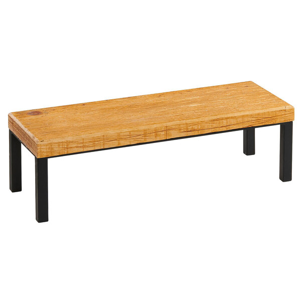A Madera rustic pine wood rectangle riser on a table with black legs.