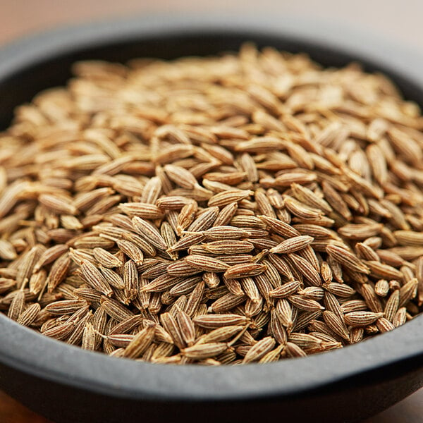 A bowl of Regal Cumin Seeds on a wooden table.