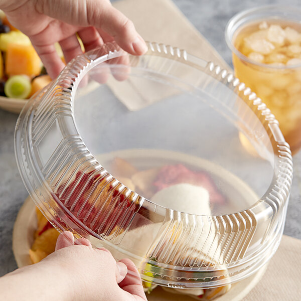 A hand holding a Tellus Products plastic container with food and a lid.
