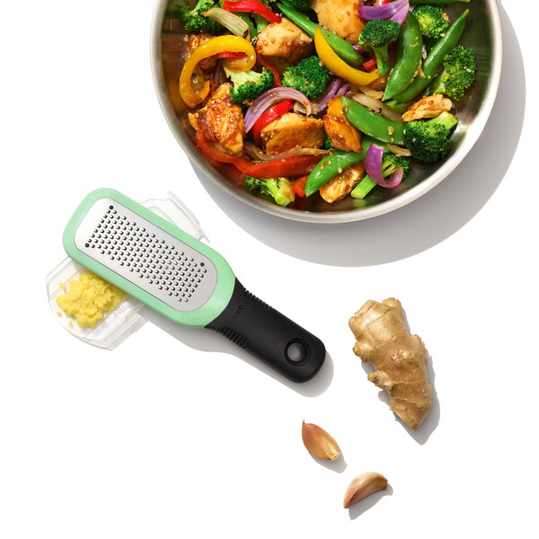 A bowl of stir fry with OXO grater next to it.