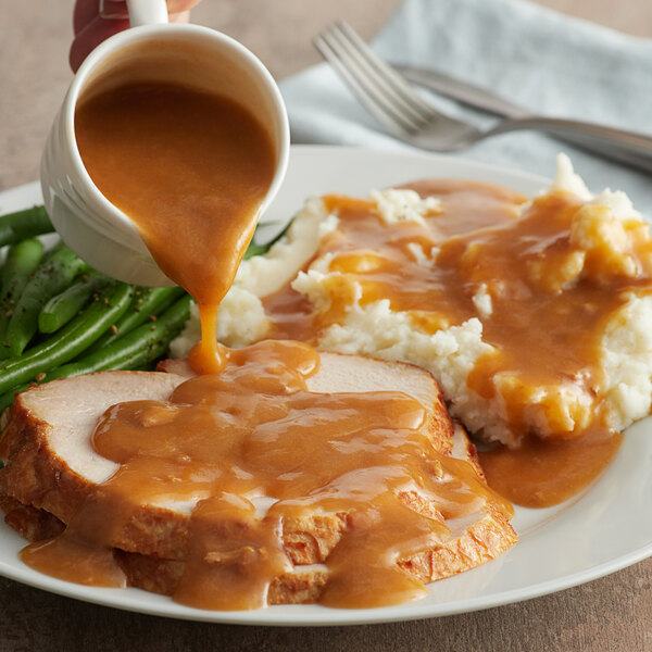A plate of turkey with LeGout turkey gravy being poured onto it.