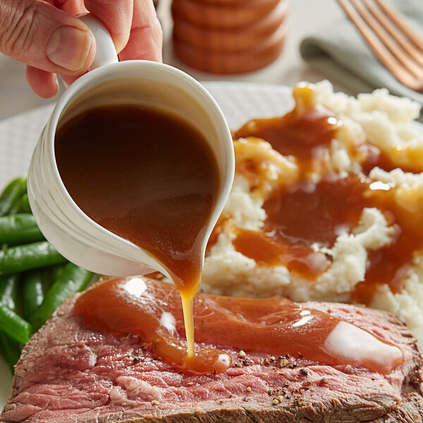 A person pouring Knorr beef gravy on a plate of meat.