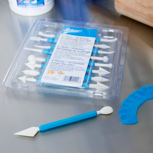 A plastic container with a blue handle and a blue plastic spatula and knife.