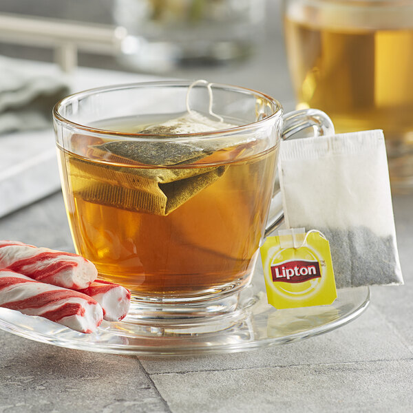 A glass cup of Lipton peppermint tea with a tea bag in it.