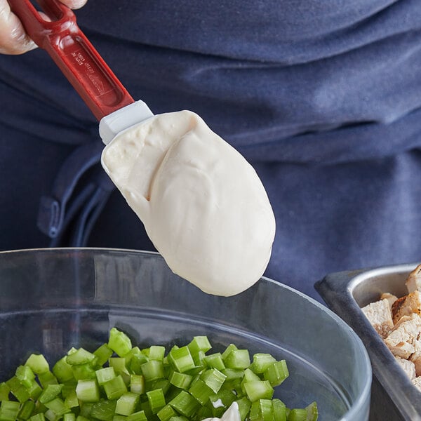 A person using a spatula to spread Hellmann's Real Mayonnaise on a bowl of food.