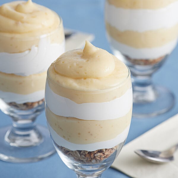 A group of LeGout Banana Cream instant pudding desserts in glasses with a spoon.