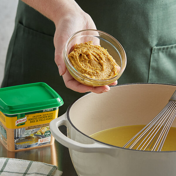 A person stirring yellow food with a whisk.