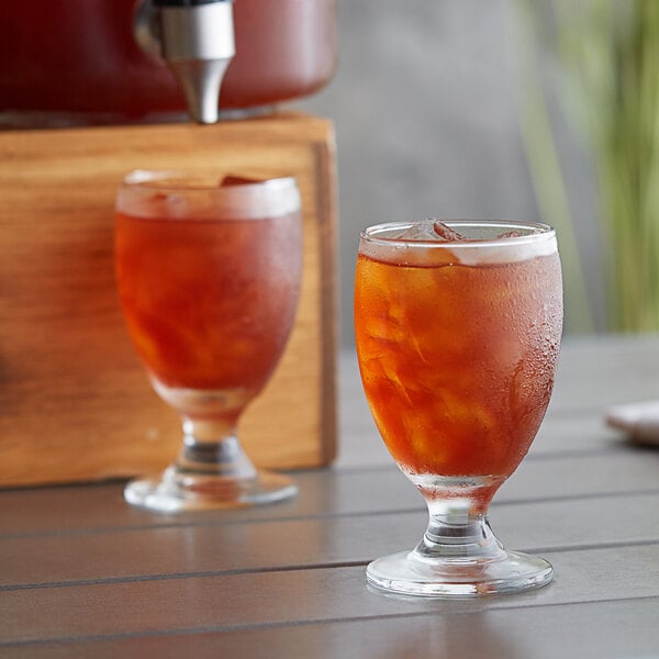 A glass of Tazo iced tea with ice cubes on a table.