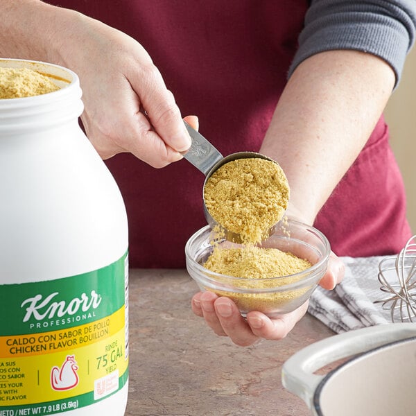 A person pouring yellow Knorr Chicken Bouillon powder into a bowl.