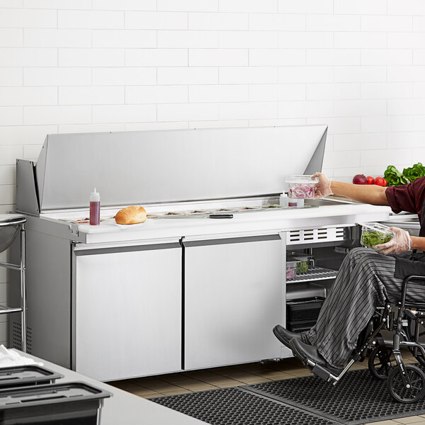 A man in a wheelchair using an Avantco ADA height refrigerator.