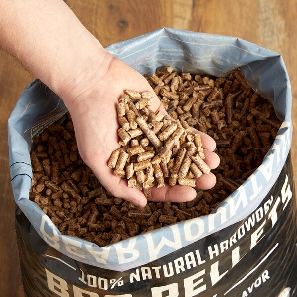 A hand holding a bag of Bear Mountain Oak BBQ pellets.