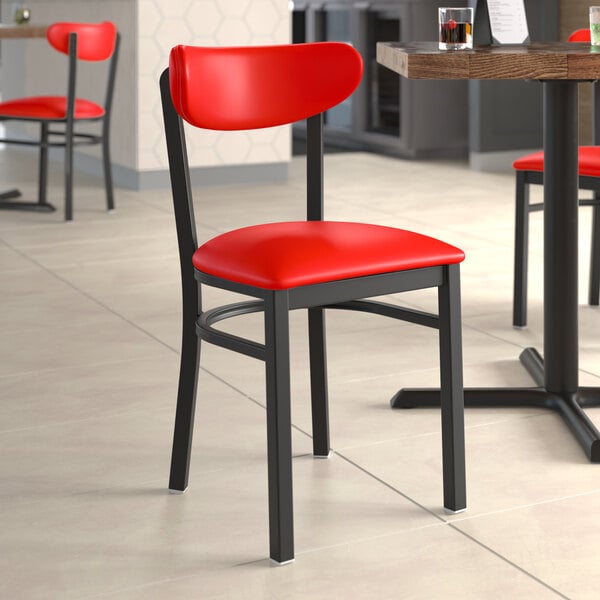 A Lancaster Table & Seating black metal chair with red vinyl seat and back.