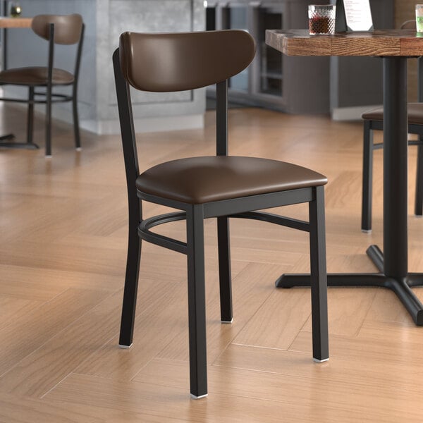 A Lancaster Table & Seating Boomerang Series black metal chair with dark brown vinyl seat and back on a table in a restaurant.