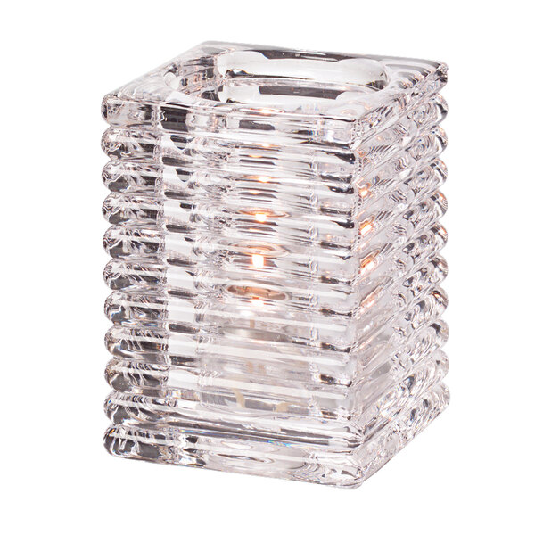 A Hollowick clear glass square candle holder with a lit candle inside.