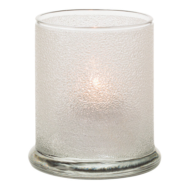 A Hollowick clear glass votive candle holder with a lit candle inside.