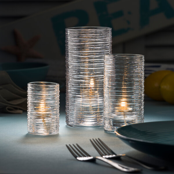 Three clear glass cylinder candle holders on a table.