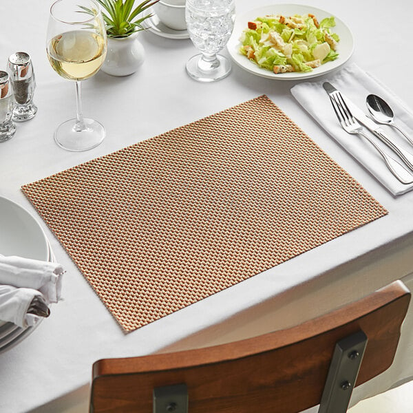 A Canyon Basketweave woven vinyl rectangle placemat with silverware and a white napkin on a table.