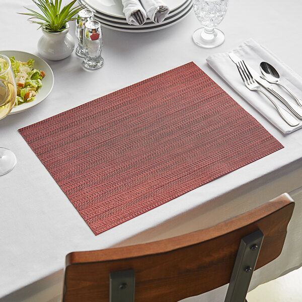 A table setting with a red Metroweave placemat and silverware.
