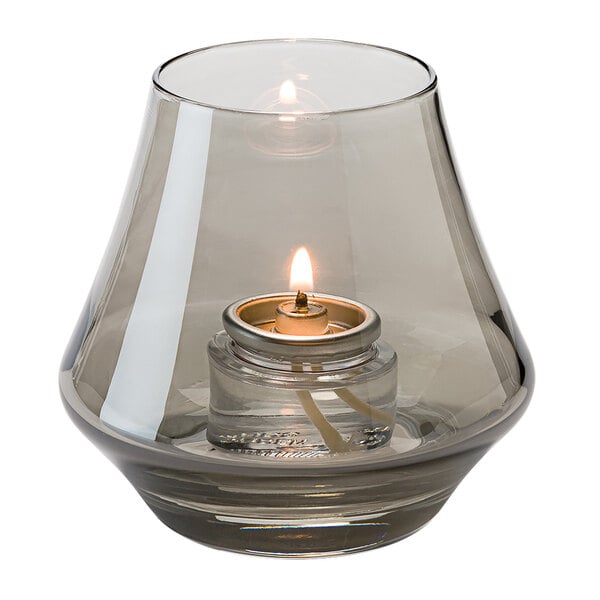 A Hollowick Chime Smoke Lustre glass votive candle holder with a lit flame inside.