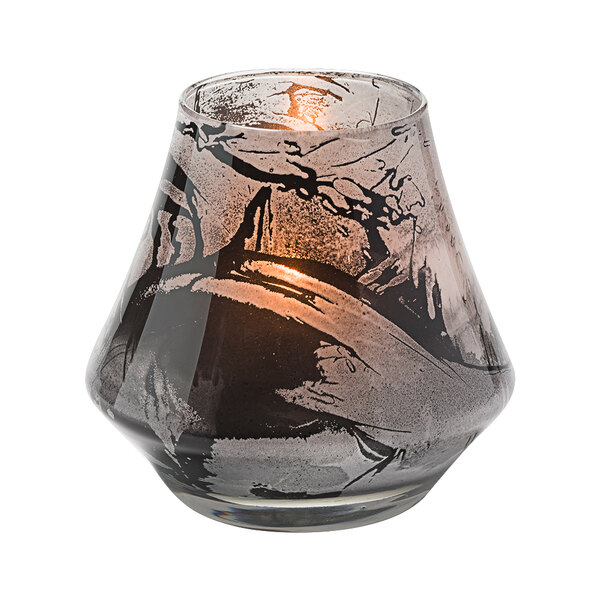 A Hollowick glass votive with a black and white marbled design holding a lit candle.