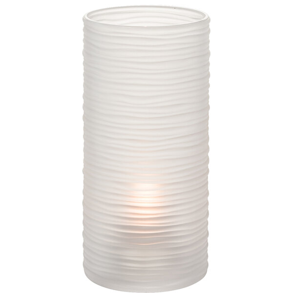 A clear glass cylinder candle holder with a lit candle inside.