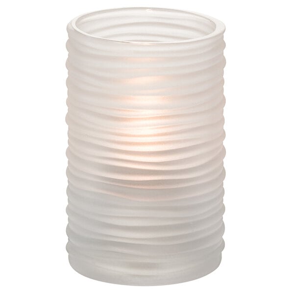 A clear glass cylinder candle holder with a lit white candle inside.