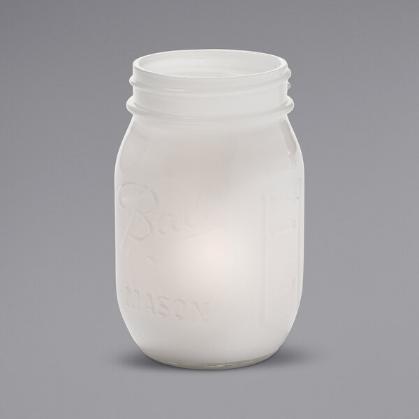 A white satin glass mason jar with a candle inside.