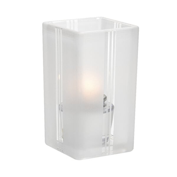 A Hollowick clear glass votive with a lit candle inside.