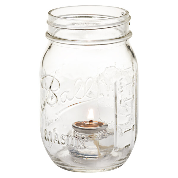 A Hollowick Firefly clear glass jar with a lit candle inside.