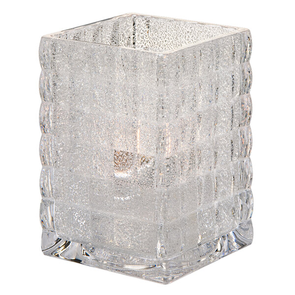 A Hollowick clear glass jewel optic block candle holder with a lit candle inside.
