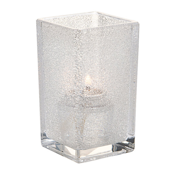 A Hollowick Quad clear glass candle holder with a lit candle inside.