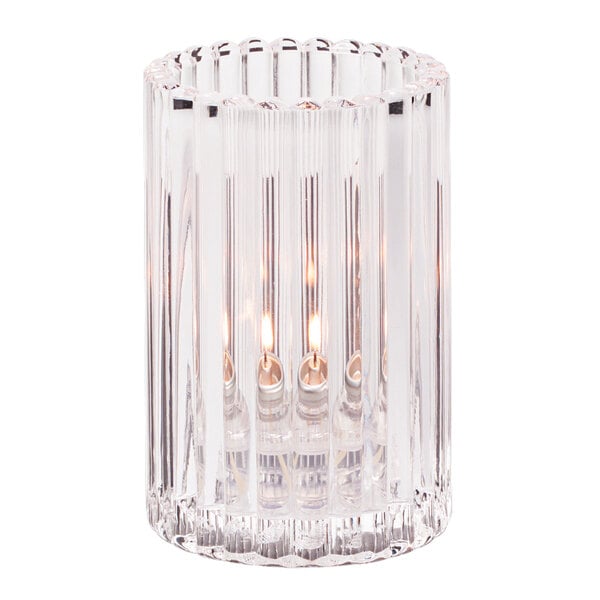 A Hollowick clear glass vertical rod candle holder with a lit candle inside.
