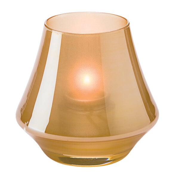 A Hollowick Satin Gold glass votive candle holder with a lit candle inside.