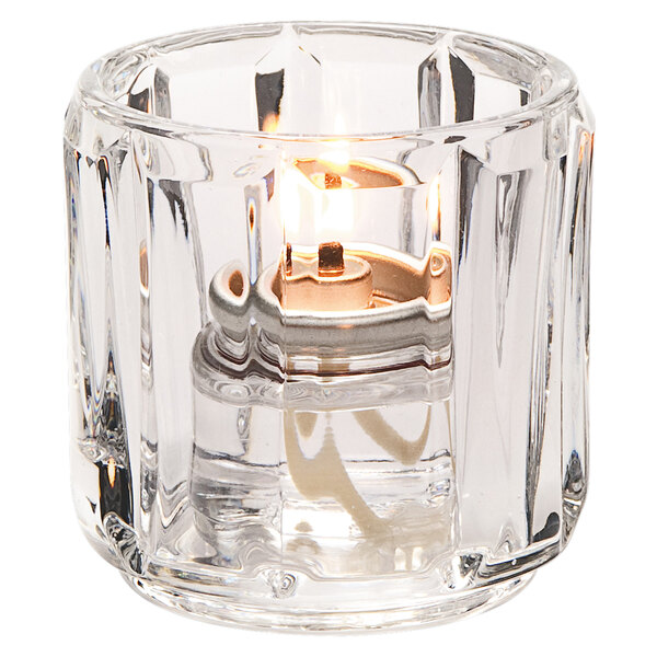 A Hollowick clear glass candle holder with a lit candle.
