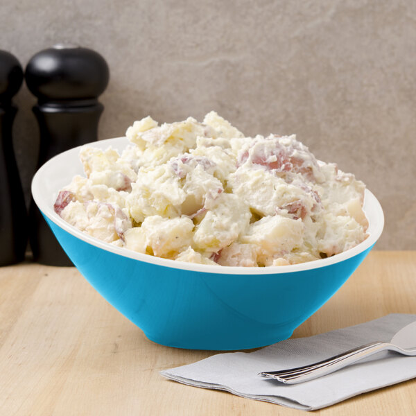 A blue GET Seabreeze melamine bowl filled with potato salad with a fork and knife.