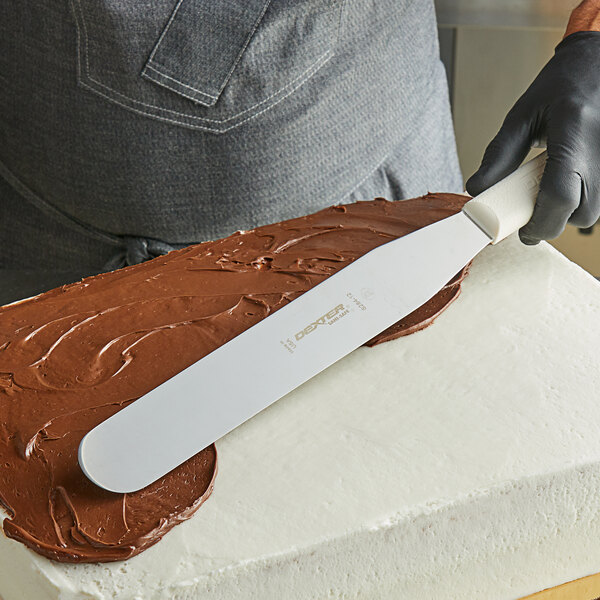 A person using a Dexter-Russell Sani-Safe straight spatula to frost a cake.