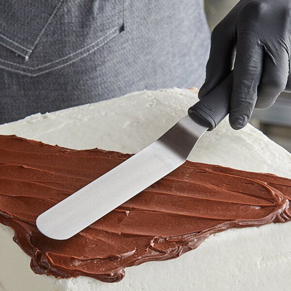 A person using an OXO Good Grips offset spatula to frost a cake.