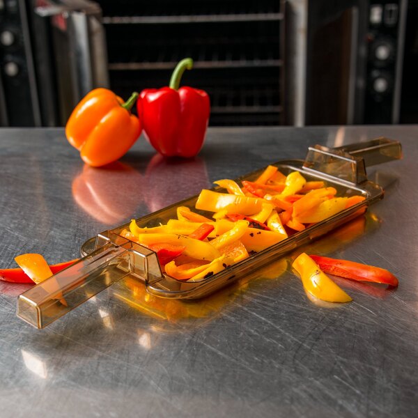 A Carlisle amber plastic food pan with carrots on a counter.